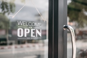 welcome we are open sign on front door of store