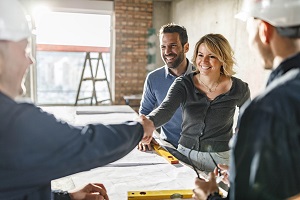 Happy couple closed a deal with manual workers at construction site.